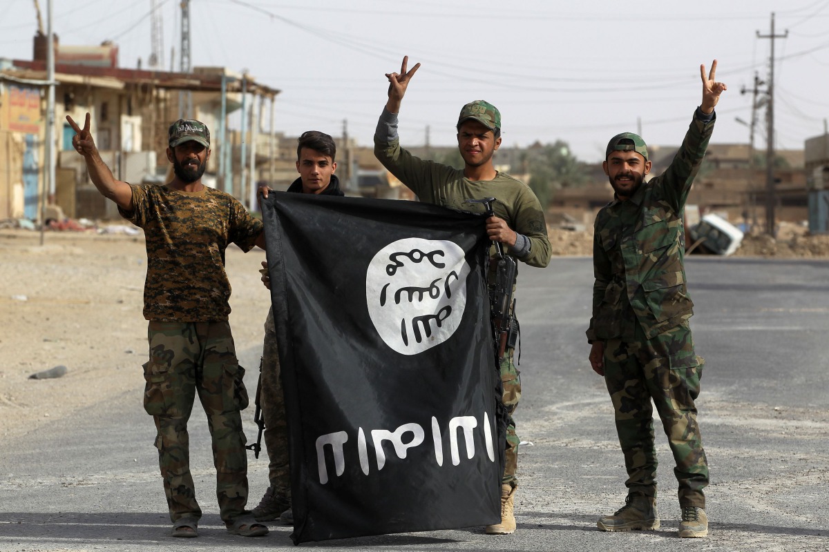 Iraqi members of the Hashed al-Shaabi (Popular Mobilisation units) carry an upsidedown Islamic State (IS) group flag in the city of al-Qaim, in Iraq's western Anbar province near the Syrian border as they fight against remnant pockets of Islamic State gro