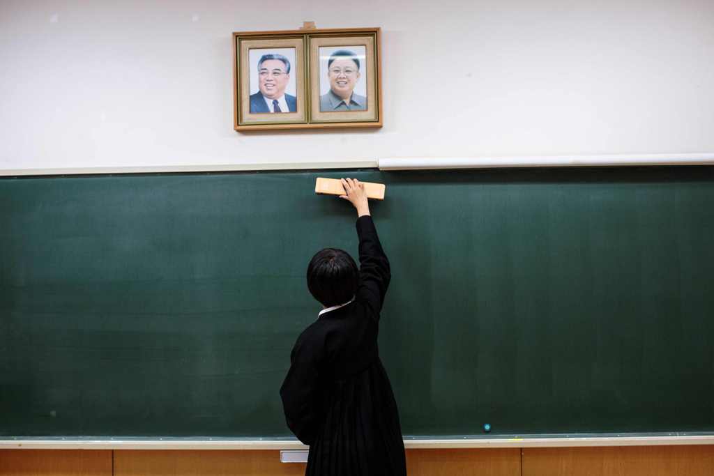 A file photo of a student cleaning the blackboard under portraits of late North Korean leaders Kim Il Sung and Kim Jong Il after an exam at Tokyo Korean high school in Tokyo October 13, 2017. / AFP / Behrouz MEHRI AND Behrouz MEHRI /