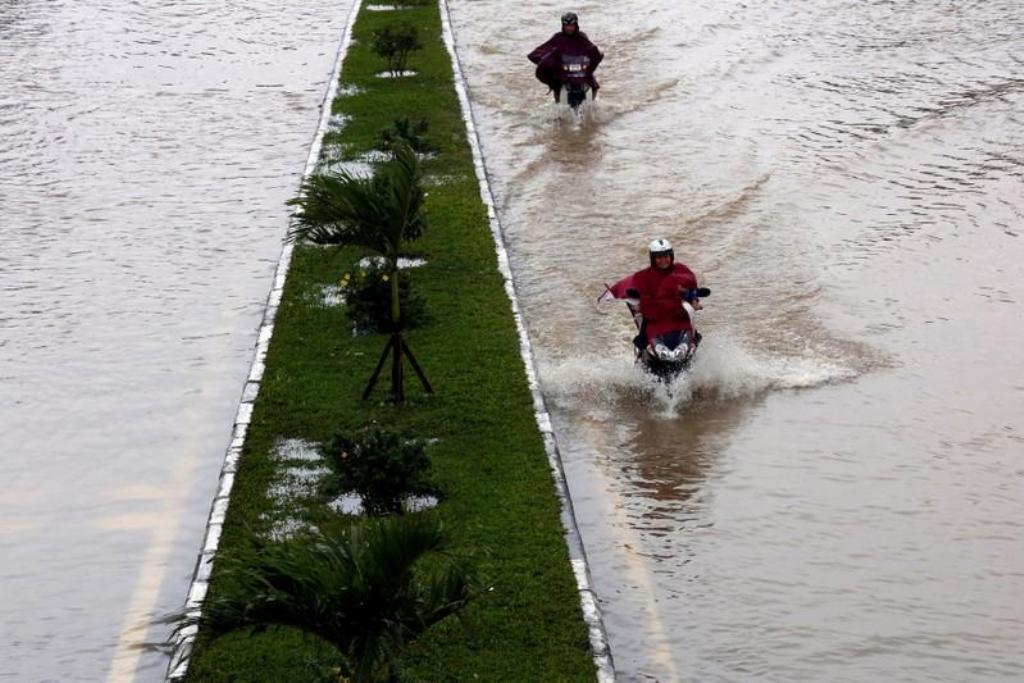 People ride motorcycles along flooded road after typhoon Damrey hits Vietnam in Hue city, Vietnam November 5, 2017. REUTERS/Kham.