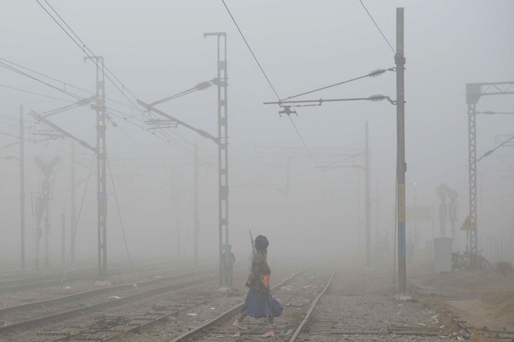 A Indian Sikh 'Nihang', or traditional Sikh army member, crosses railway tracks amidst dense smog near Amritsar railway station on November 7, 2017. / AFP / NARINDER NANU