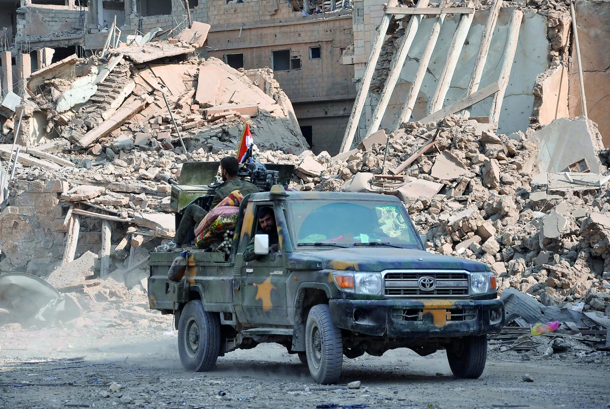 Syrian pro-government forces patrol in the eastern city of Deir Ezzor on November 4, 2017. Syrian and allied forces converged on holdout Islamic State group fighters in the Syrian border town of Albu Kamal, the jihadists' very last urban bastion following