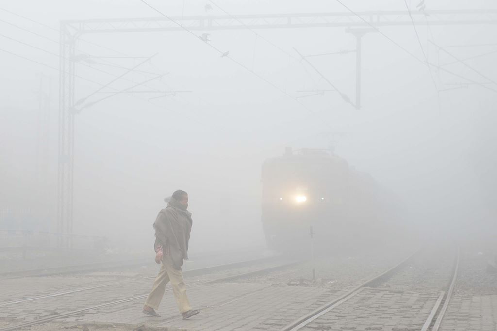 An Indian resident walks over the tracks at a railway crossing amid heavy smog in Amritsar on November 9, 2017. AFP / NARINDER NANU
