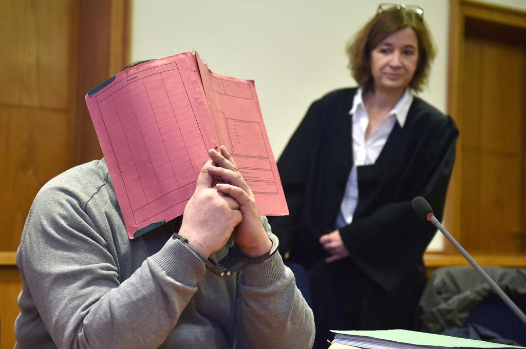 German former male nurse Niels Hoegel hiding his face behind a folder as he waits next to his lawyer Ulrike Baumann (R) for the opening of another session of his trial at court in Oldenburg, northwestern Germany. File photo taken on February 26, 2015. (AF