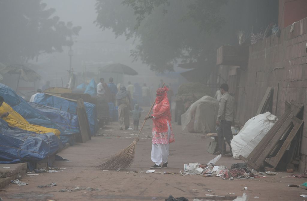 An Indian sweeper cleans a road amid heavy smog in New Delhi on November 8, 2017.  AFP / SAJJAD HUSSAIN
