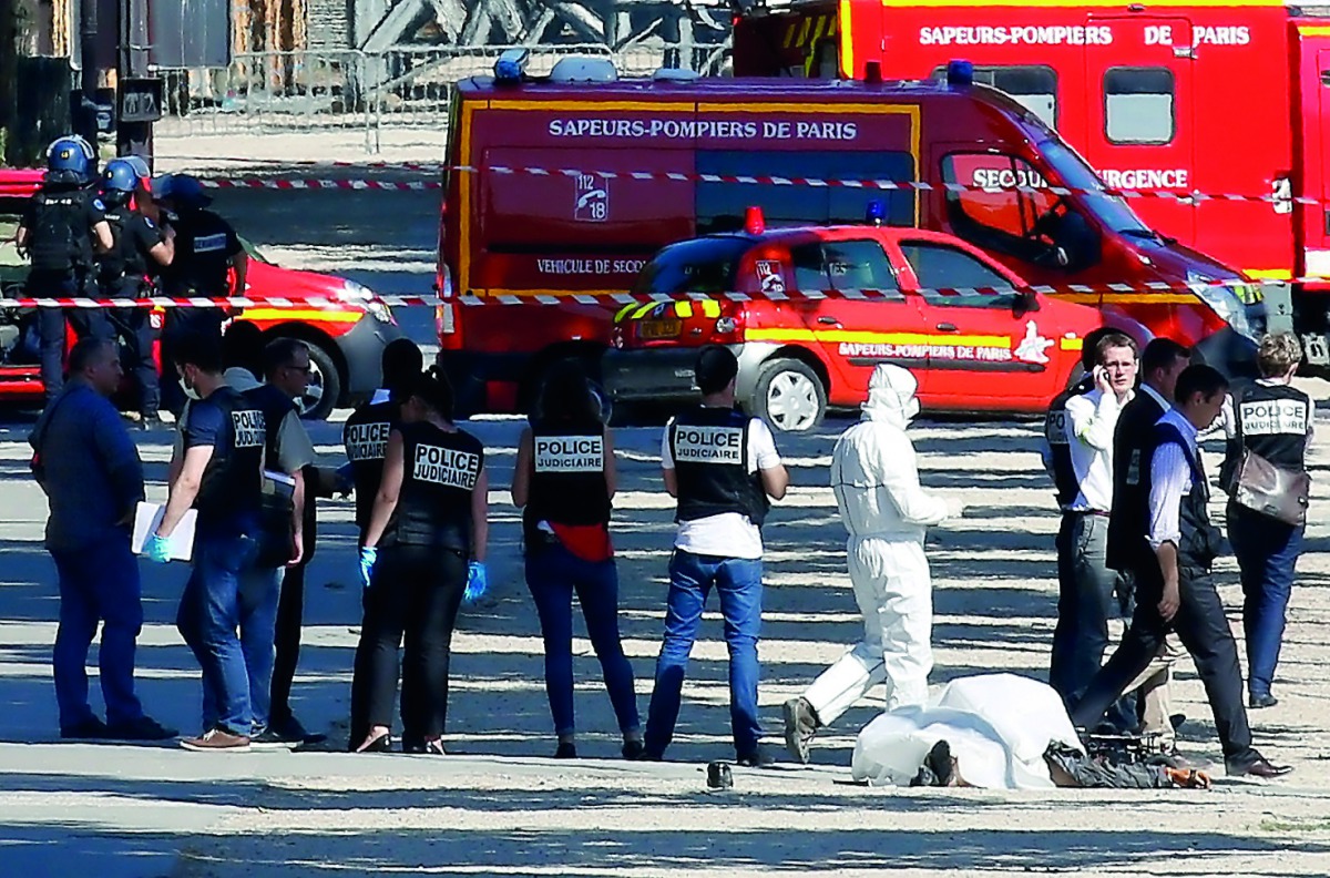 FILE PHOTO: Criminal police inspect the body of a suspect at the scene of an incident in which a car rammed a gendarmerie van on the Champs-Elysees Avenue in Paris, June 19, 2017 (Reuters / Gonzalo Fuentes) 