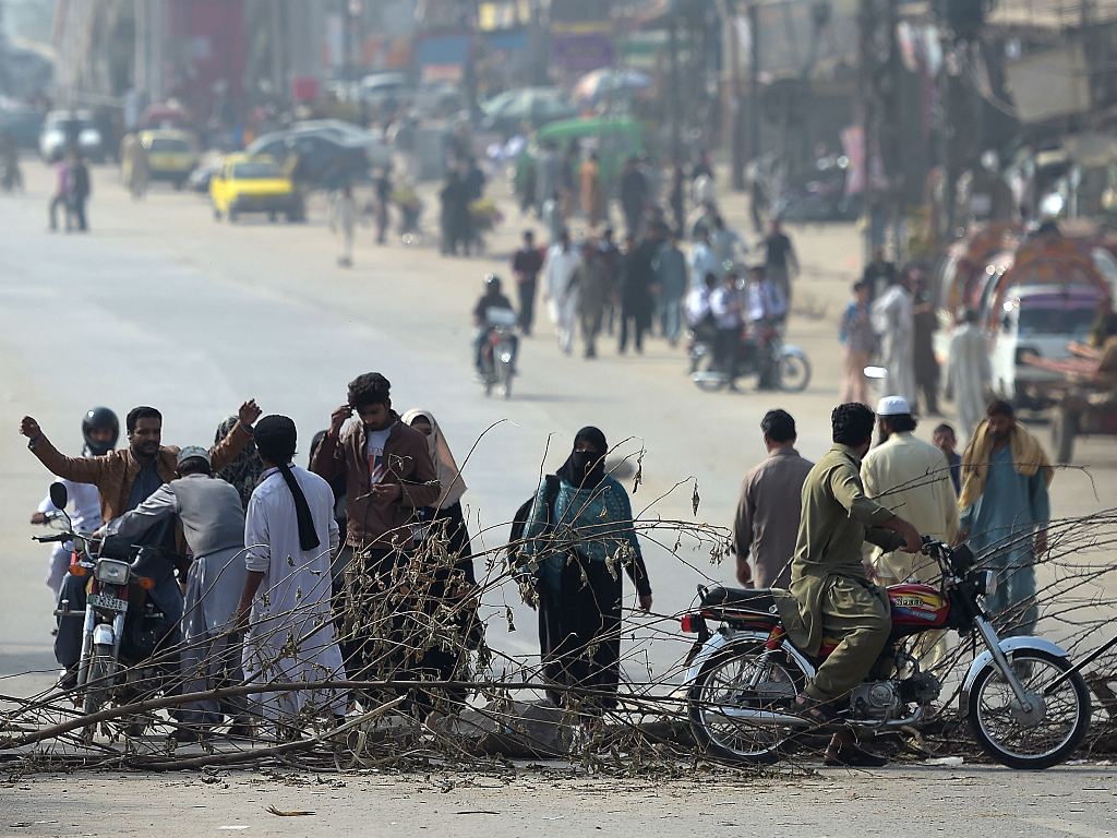 Pakistani activists of the Tehreek-i-Labaik Yah Rasool Allah Pakistan (TLYRAP) religious group search a motorcyclist along a blocked highway during a week long protest in Islamabad on November 13, 2017. (AFP / AAMIR QURESHI)