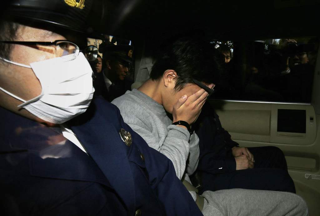 (FILES) This file photo taken on November 1, 2017 shows suspect Takahiro Shiraishi (C) covering his face with his hands as he is transported to the prosecutor's office from a police station in Tokyo. AFP / JIJI PRESS / STR 