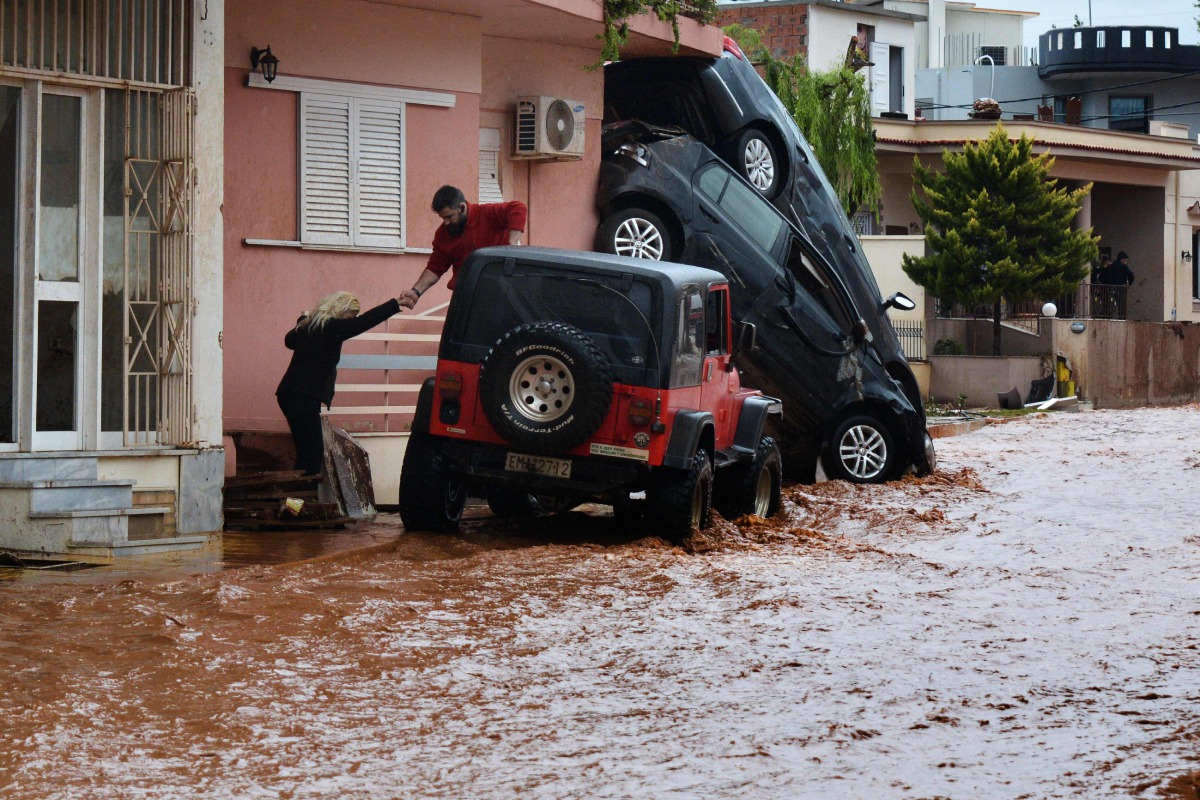 A man helps evacuate a woman from a flooded street in Mandra, northwest of Athens, on November 16, 2017. AFP / Dimitris Lambropoulos