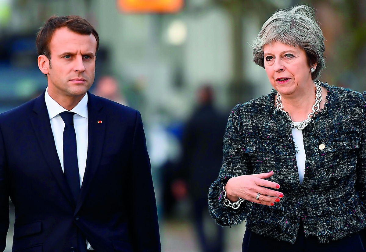 France's President Emmanuel Macron (L) and Britain's Prime minister Theresa May talk while walking to the luncheon during the European Social Summit in Gothenburg, Sweden, on November 17, 2017. AFP / Jonathan Nackstrand