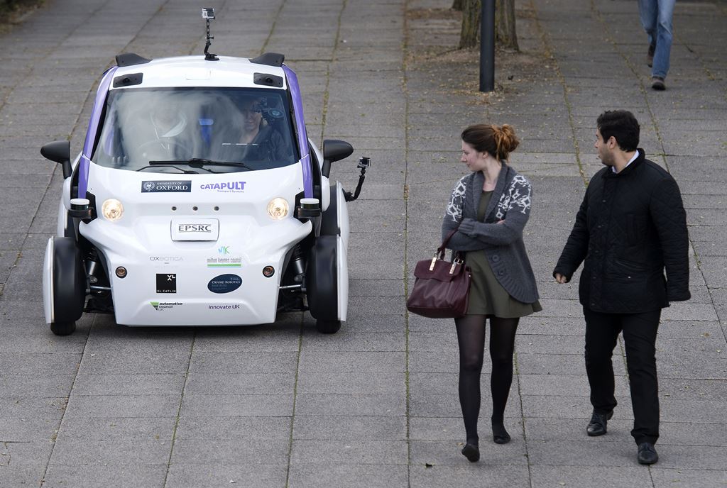(FILES) This file photo taken on October 11, 2016 shows people looking at an autonomous self-driving vehicle, as it is tested in a pedestrianised zone, during a media event in Milton Keynes, north of London, on October 11, 2016. A driverless, electric car