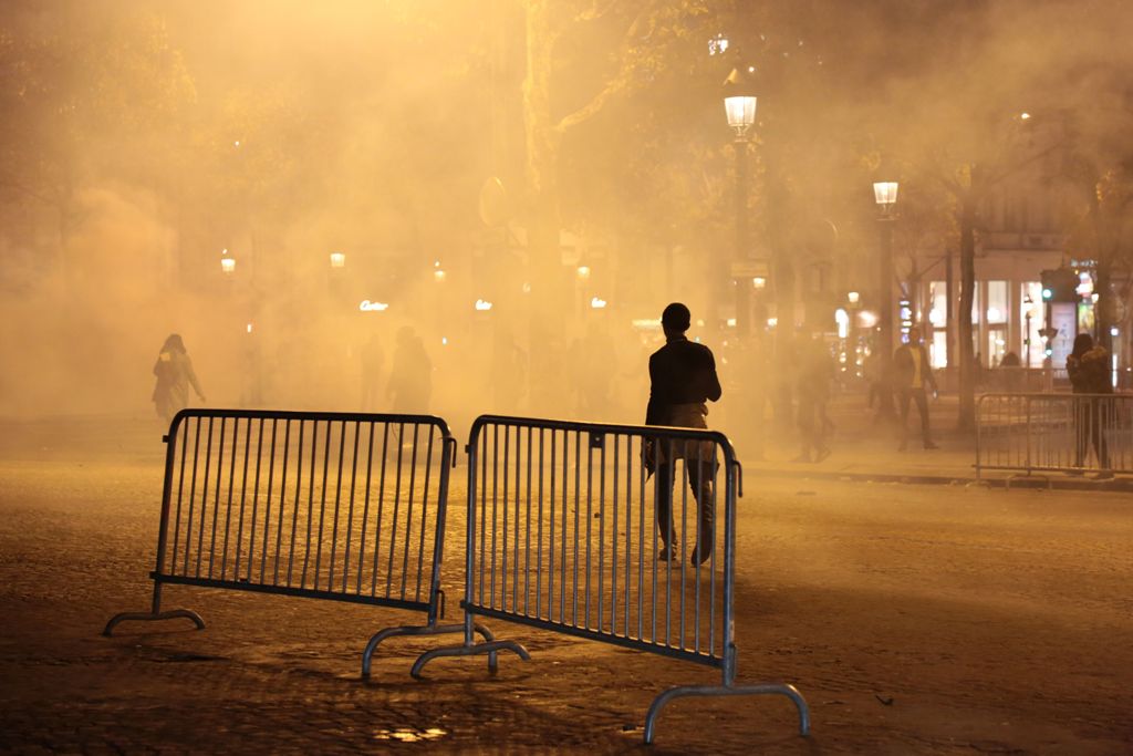 A demonstrator, standing through the smoke from tear gas, walks on the Champs-Elysees avenue in Paris, during a march against 