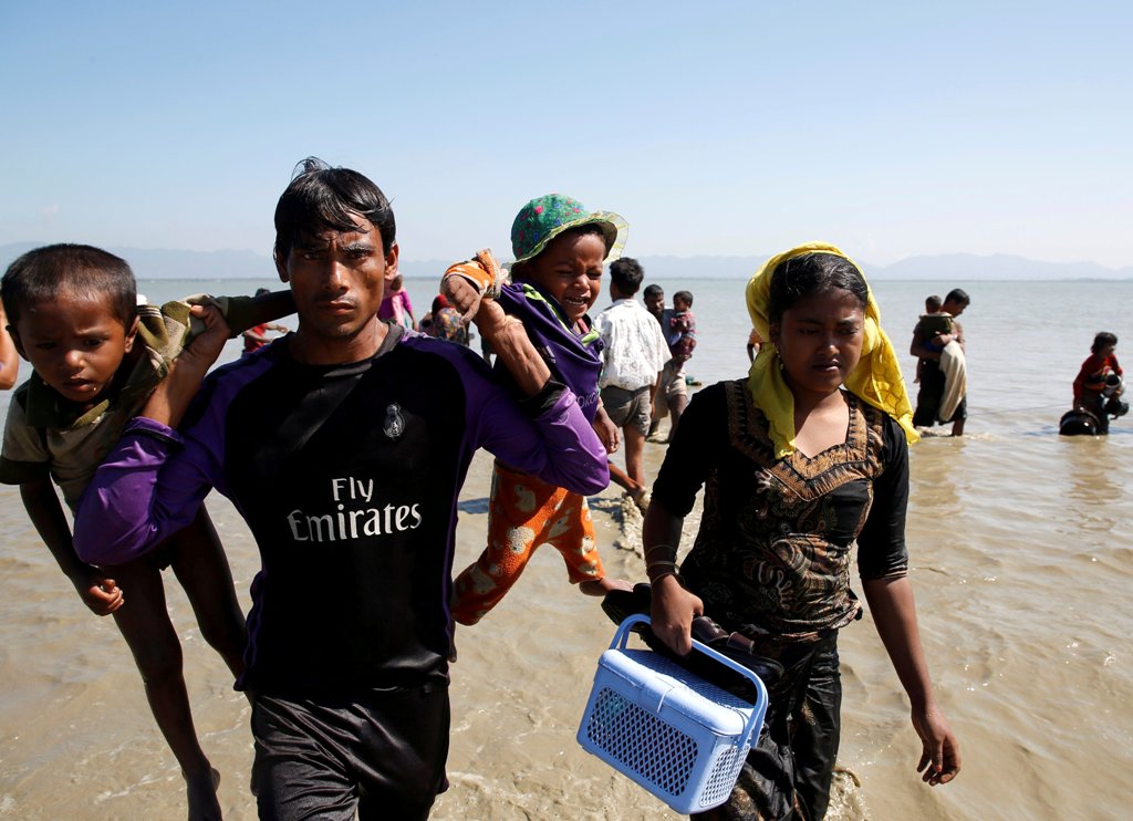 A Rohingya refugee man holding children walks towards the shore as they arrive on a makeshift boat after crossing the Bangladesh-Myanmar border, at Shah Porir Dwip near Cox's Bazar, Bangladesh, November 9, 2017. REUTERS/Navesh Chitrakar