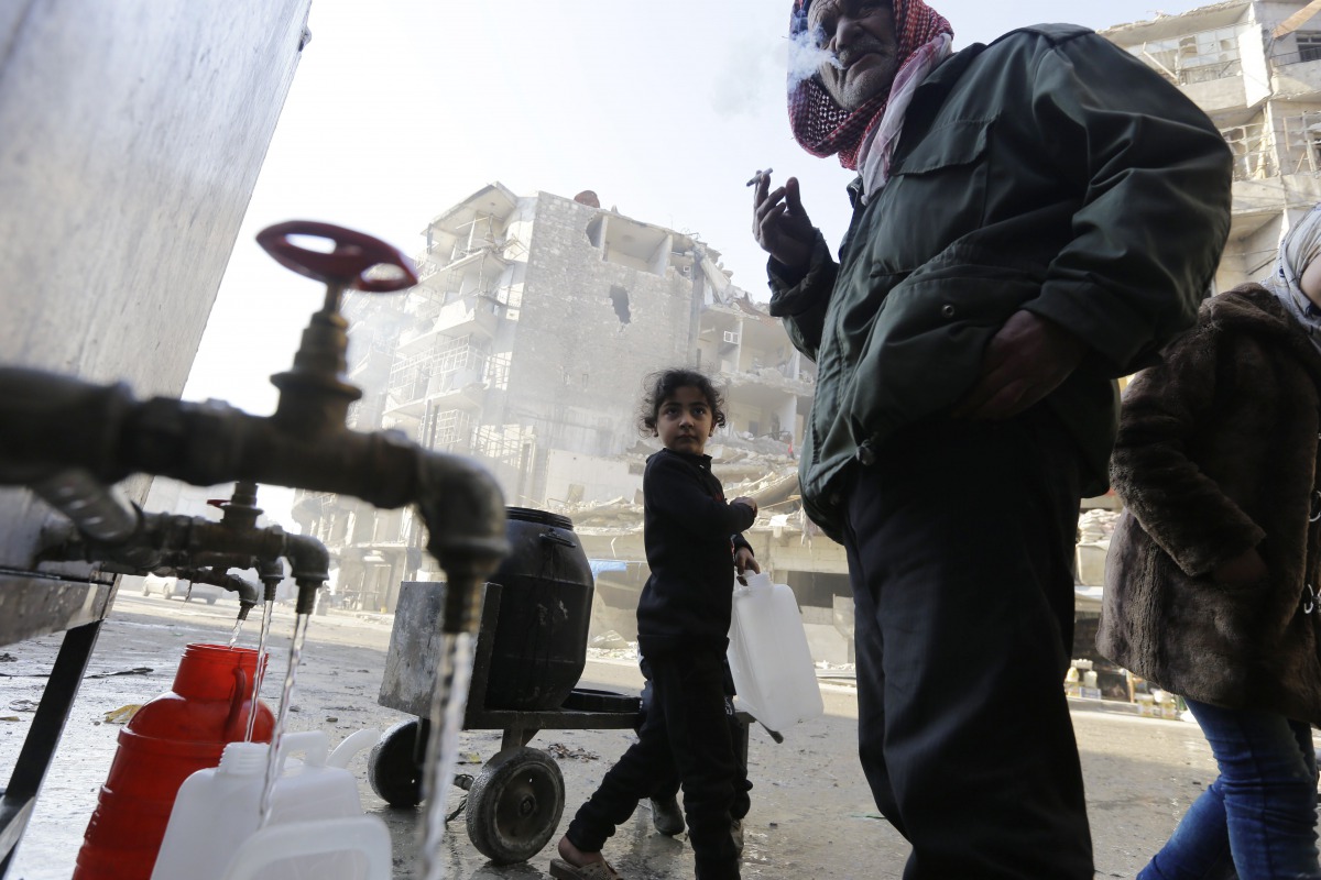 Syrians standing next to water faucets as they fill jerrycans in al-Shaar neighbourhood, Aleppo on January 21, 2017 (AFP / Louai Beshara) 