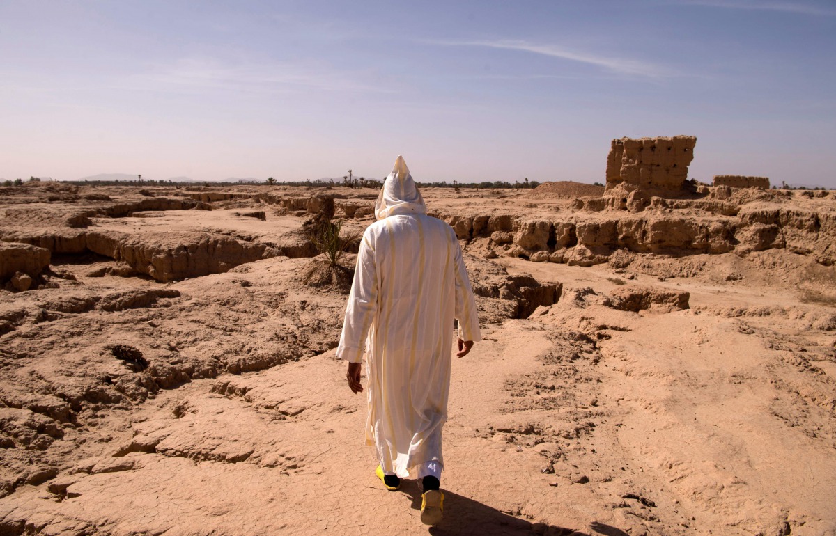 This file photo taken on October 27, 2016 shows a man walking through a dried out area, that used to be part of the Tafilalet oasis, near Morocco's southeastern oasis town of Erfoud, north of Er-Rissani in the Sahara Desert.  AFP / Fadel Senna  

