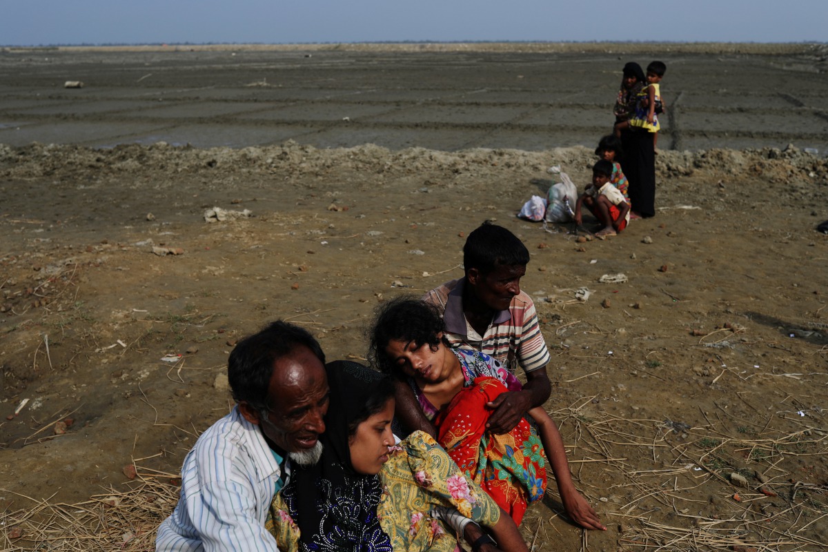 Rohingya refugees Minara Begum, 19, and Taslima, 18, are helped by relatives after collapsing from exhaustion hours after crossing the Bangladesh-Myanmar border at Shah Porir Dwip near Cox's Bazar, Bangladesh, November 23, 2017. Reuters/Susana Vera  

