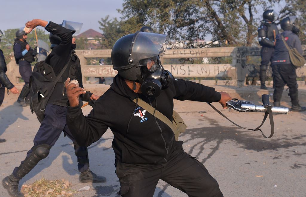 A Pakistani riot policeman throws a rock toward protesters of the Tehreek-i-Labaik Yah Rasool Allah Pakistan (TLYRAP) religious group during a protest in Islamabad on November 25, 2017. AFP / AAMIR QURESHI
