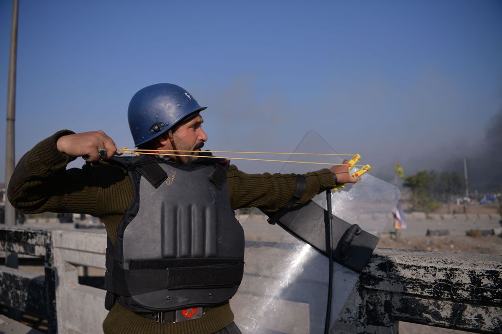 A Pakistani policeman uses a slingshot during clashes with activists from the Tehreek-i-Labaik Yah Rasool Allah Pakistan (TLYRAP) religious group in Islamabad on November 25, 2017. AFP / AAMIR QURESHI