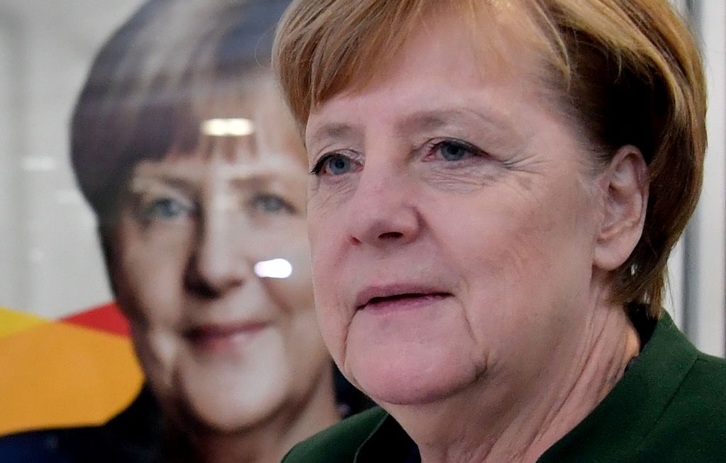 German Chancellor Angela Merkel walks past a poster of herself as she arrives to give a press conference on November 27, 2017 in Berlin, following a meeting with her conservative Christian Democratic Union (CDU) party's leadership.  AFP / John MACDOUGALL