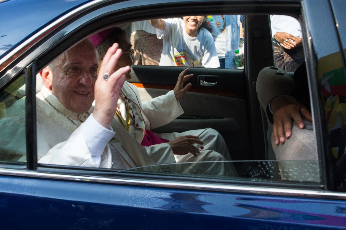 Pope Francis waves to well-wishers as he is driven through the streets of downtown Yangon on November 27, 2017. Pope Francis arrived in mainly Buddhist Myanmar on November 27 where he was set to meet army chief Min Aung Hlaing, the man accused of overseei