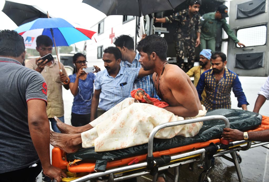 Indian officials carry a stranded fisherman, rescued by naval and air force helicopters from the Ockhi cyclone, at Thiruvananthpuram airport on December 1, 2017. / AFP / Rakesh Nair