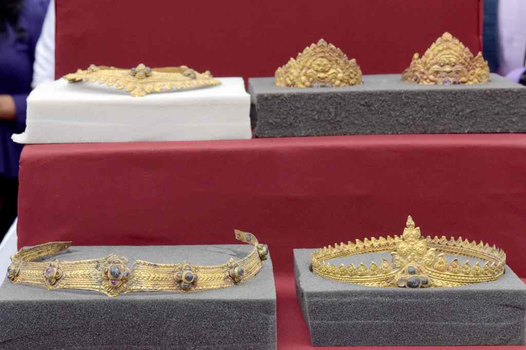A set of returned Angkorian-era gold jewellery is displayed to the public behind protective glass during a ceremony in front of the National Museum upon its arrival in Phnom Penh on December 2, 2017. /AFP /TANG CHHIN SOTHY