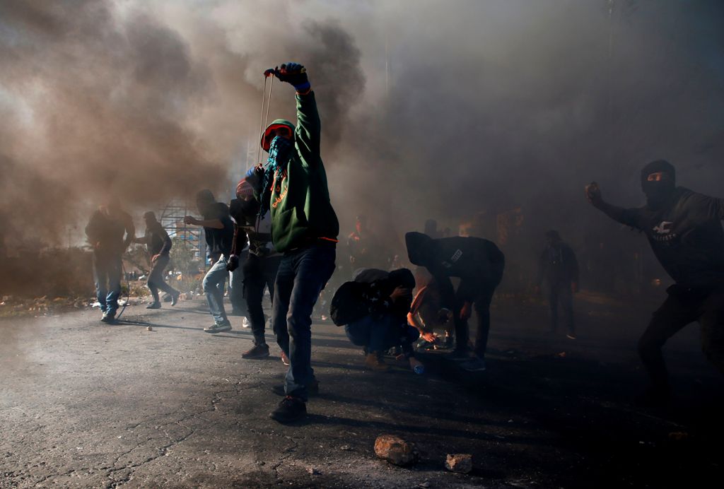 Palestinian protesters clash with Israeli troops near an Israeli checkpoint in the West Bank city of Ramallah on December 8, 2017.  AFP / ABBAS MOMANI