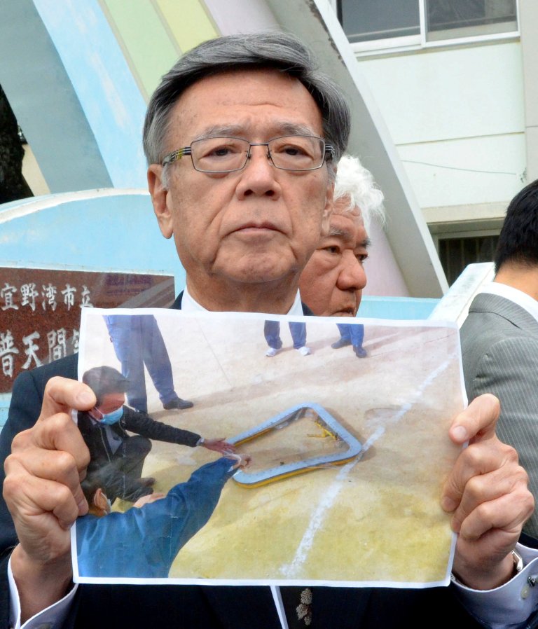 Okinawa Governor Takeshi Onaga shows a picture of a window that fell from a US helicopter onto a school sports field in front of the Futenma Daini Elementary School in Ginowan, Okinawa prefecture, Japan December 13, 2017. Kyodo/via REUTERS