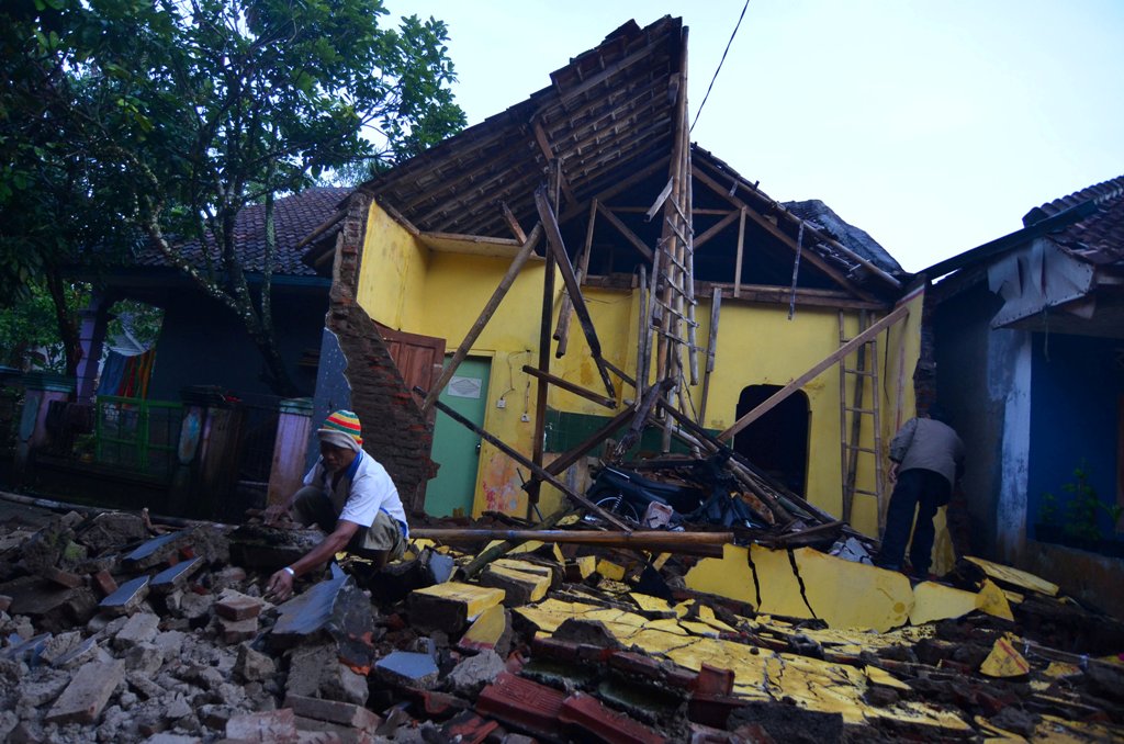 A man cleans up the wreckage of a house damaged by an earthquake in Sumelap Village, Tasikmalaya City, West Java, Indonesia December 16, 2017 in this photo taken by Antara Foto. / Reuters.