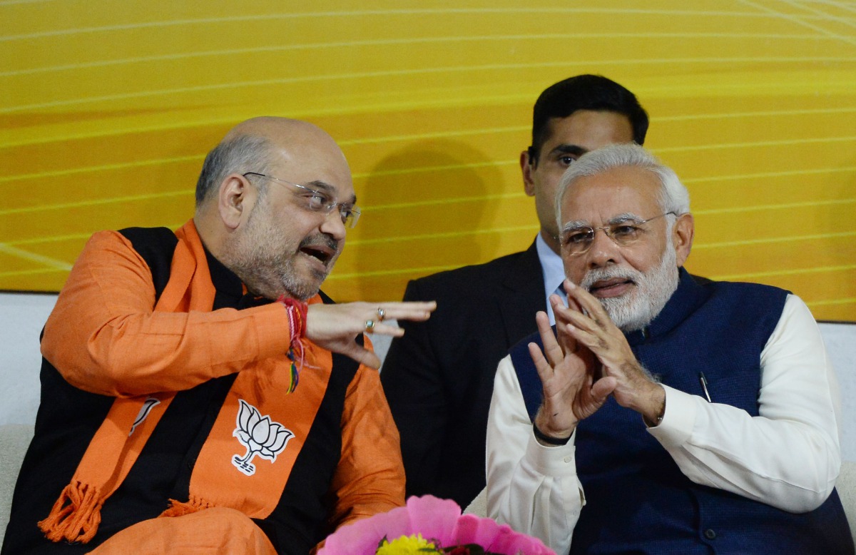 Indian Prime Minister and head of the Bharatiya Janata Party (BJP) Narendra Modi (R) and party president Amit Shah talk at the start of a speech at the party headquarters in New Delhi on December 18, 2017. (AFP / SAJJAD HUSSAIN)
