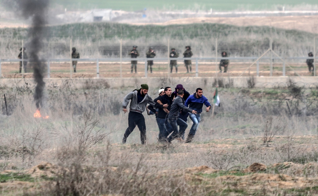 Palestinian protesters carry their wounded friend during a demonstration against US President Donald Trump's recognition of Jerusalem as Israel's capital, at Israeli border in Shuja'iyya neighborhood of Gaza City, December 22, 2017. ( Ali Jadallah - Anado