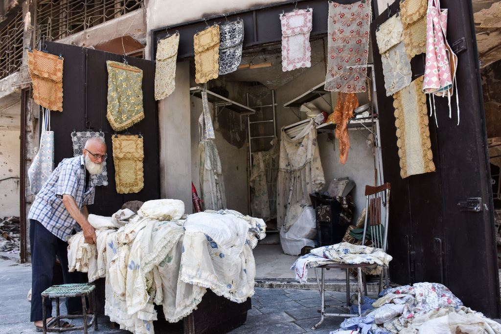 A picture taken on July 22, 2017, shows 62-year-old Mohammad Shawash sitting outside his textile shop amid the destruction in the old city of Aleppo. AFP / George OURFALIAN