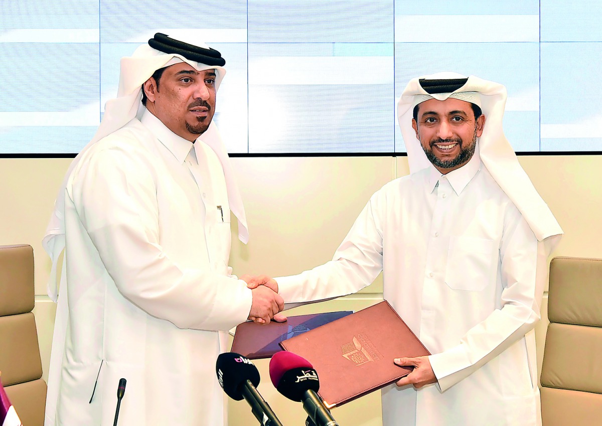 QU President, Dr Hassan Al Derham, and QLC Deputy Manager Director and Director of Administration and Finance, Dr Ali Jassim Al Kubaisi, exchanging documents during the signing ceremony.