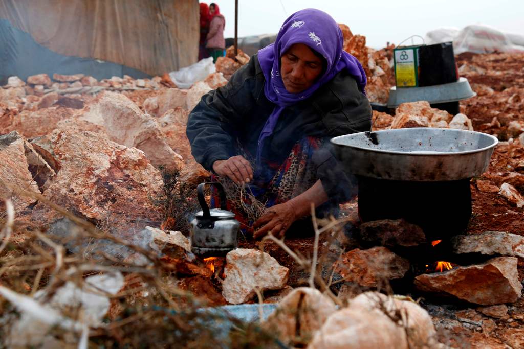 A Syrian woman, who fled from the outskirts of southern Idlib due to the conflict between government forces and opposition fighters, cooks over a fire at the make-shift camp of Kalbeed near the Bab al-Hawa crossing on the Syria-Turkey border on January 17