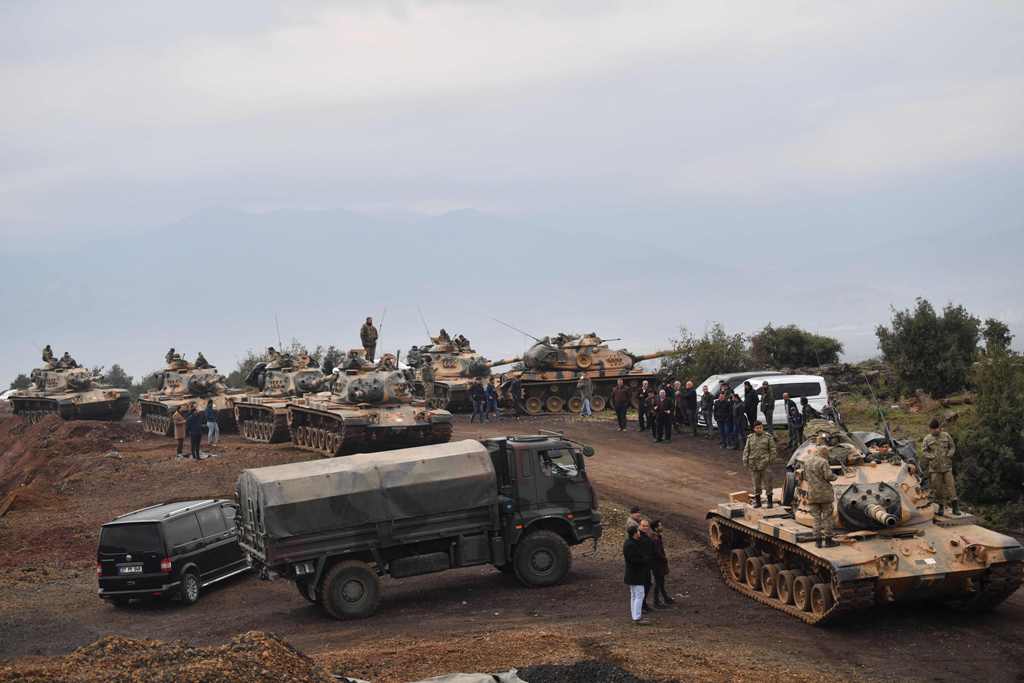 Villagers watch as Turkish army tanks and soldiers gather near the Syrian border on January 21, 2018 at Hassa, in Hatay province.  AFP / BULENT KILIC
