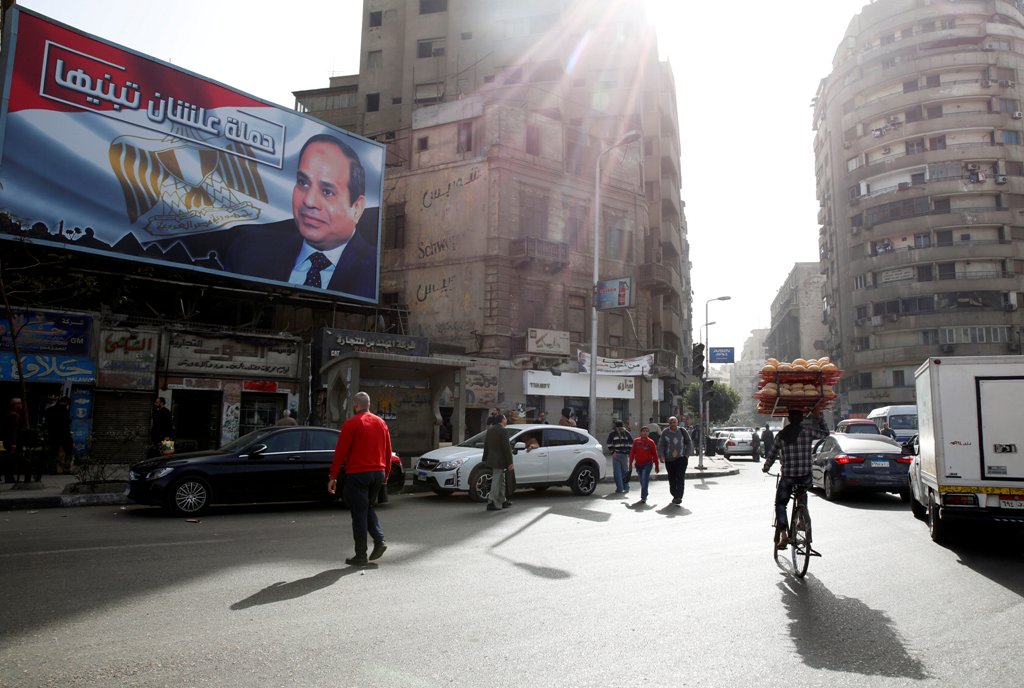 People walk by a poster of Egypt's President Abdel Fattah al-Sisi from the campaign titled 