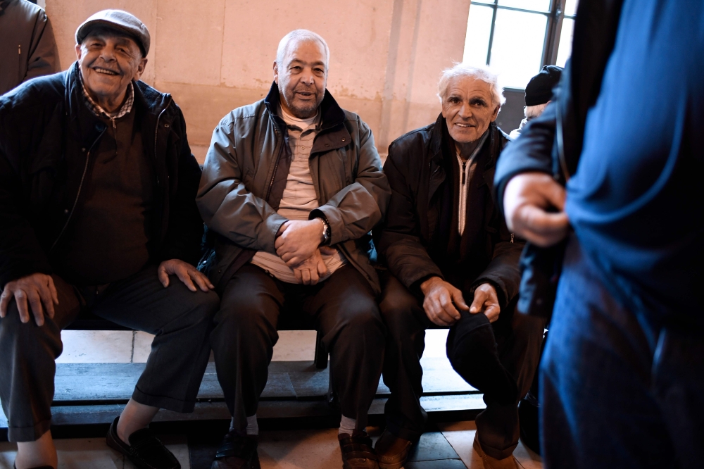 People sit outside the Court of Appeal in Paris on January 31, 2018 after former workers won in a discrimination claim made by more than 800 railway workers (Chibanis) of Moroccan nationality or origin against France's national railway company SNCF.  AFP 