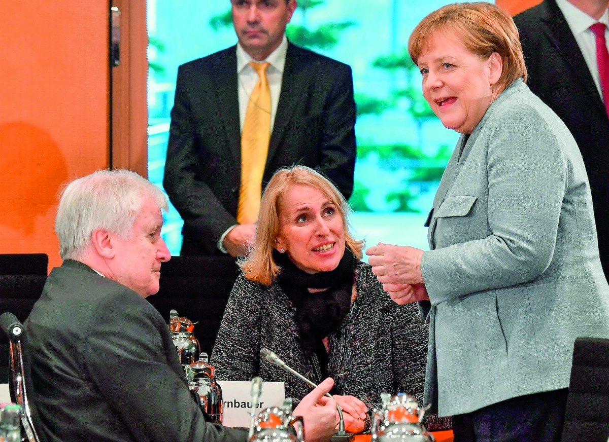 German Chancellor Angela Merkel (R) speaks with Chairman of the Bavarian Christian Social Union (CSU) Horst Seehofer (L) and the Office chief of Bavaria's state chancellery Karolina Gernbauer prior to a meeting with German regional state leaders as part o