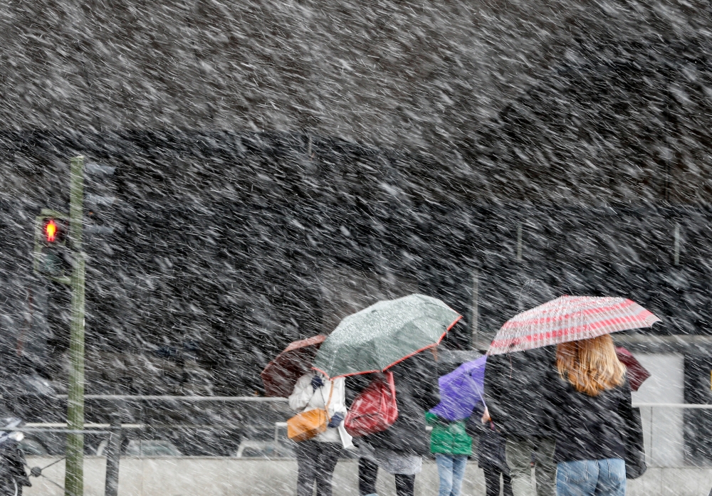 People cross a street during a heavy snowfall in Madrid, Spain, February 5, 2018. Reuters/Paul Hanna