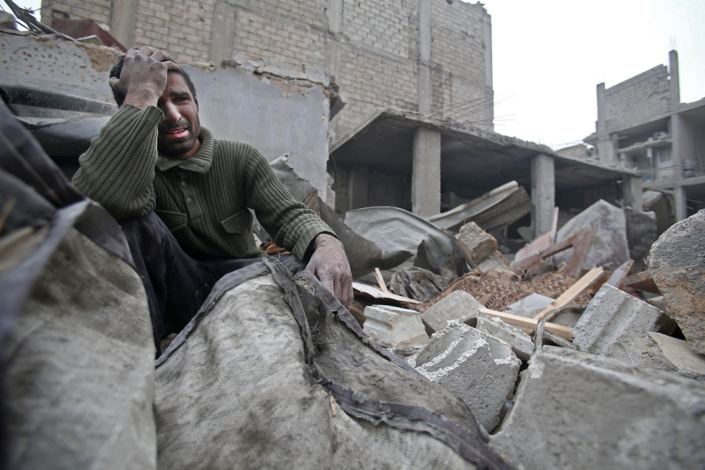 A Syrian man mourns over his destroyed home in the rebel-held besieged town of Arbin, in the eastern Ghouta region on the outskirts of the capital Damascus on February 5, 2018, following airstrikes. / AFP / ABDULMONAM EASSA