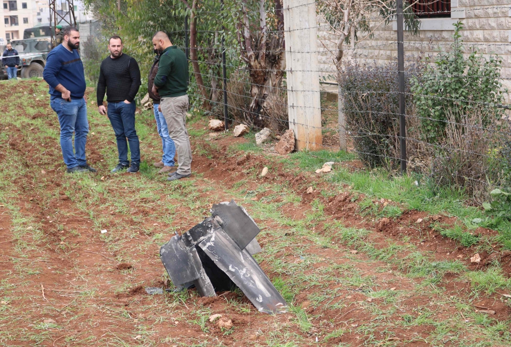 Unidentified men stand next to a piece from a missile that landed on February 10, 2018 in the eastern Lebanese town of Rayak, near the border with Syria in the Bekaa Valley. AFP / HASSAN JARRAH