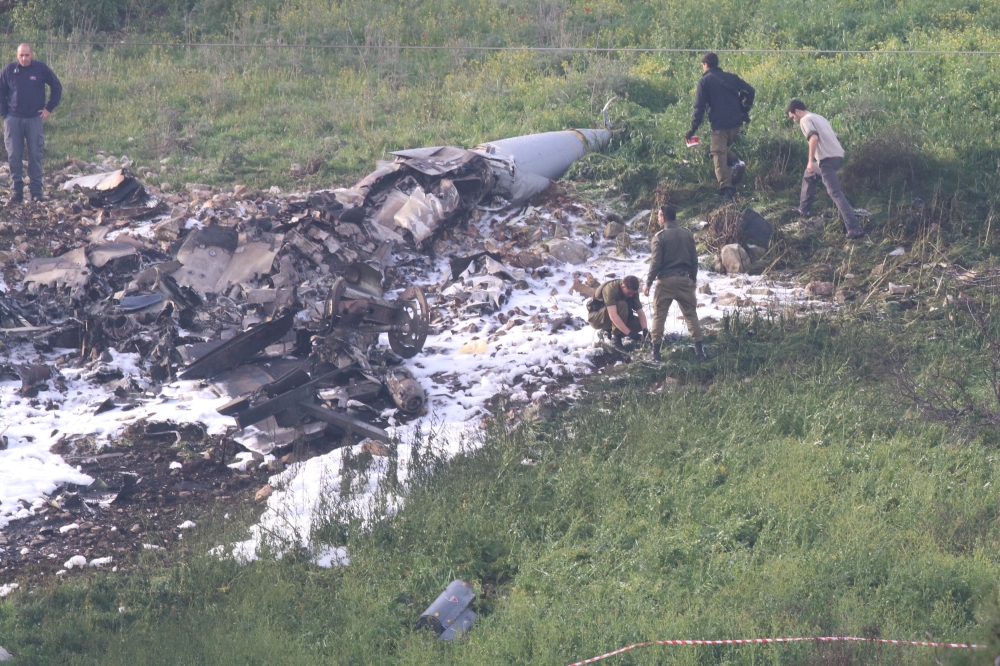 Israeli security forces walk next to the remains of an F-16 Israeli war plane near the Israeli village of Harduf, Israel February 10, 2018. REUTERS/Herzie Shapira ISRAEL OUT.
