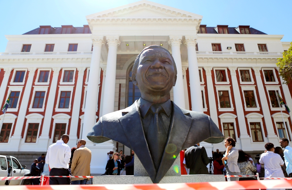 Members of the media are seen behind a bust of Nelson Mandela outside Parliament after it was announced that the State of the Nation address, due to be delivered by President Jacob Zuma, has been postponed, in Cape Town, South Africa, February 6, 2018. Re