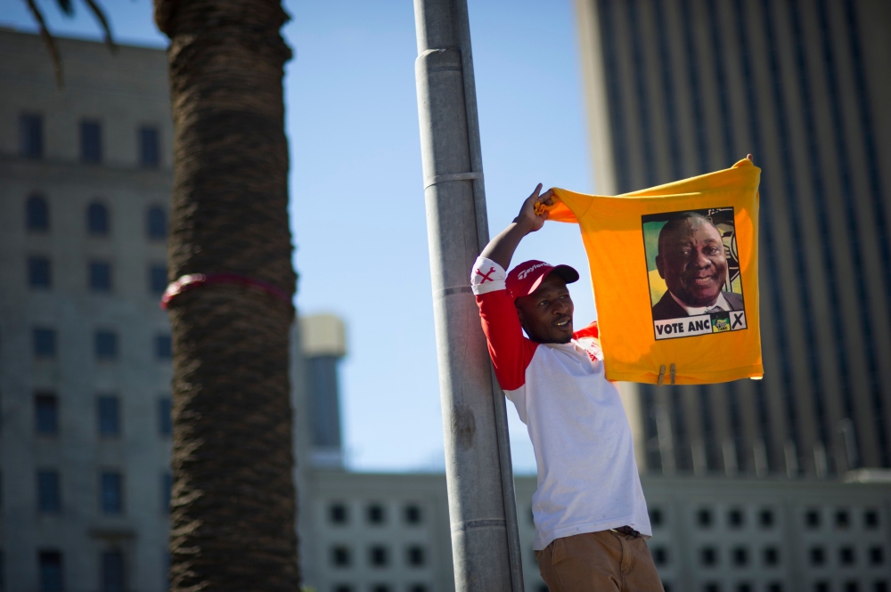 A supporter of South Africa's ruling African National Congress (ANC) holds up a shirt featuring newly-elected ANC president and South African Deputy President, Cyril Ramaphosa, during a rally on February 11, 2018 in Cape Town, from the same spot where exa