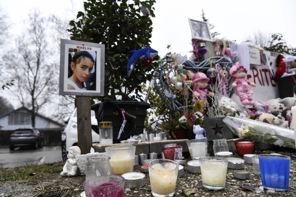 A picture taken on February 15, 2018, in Le Pont-de-Beauvoisin, shows a picture of eight-year-old Maelys de Araujo, candles, toys and messages displayed in tribute to the schoolgirl at the place where was seen for the last time.  AFP / Philippe Desmazes