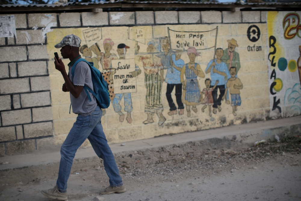 A man walks past an Oxfam sign in Corail, a camp for displaced people of the 2010 earthquake, on the outskirts of Port-au-Prince, Haiti, February 13, 2018. Reuters/Andres Martinez Casares