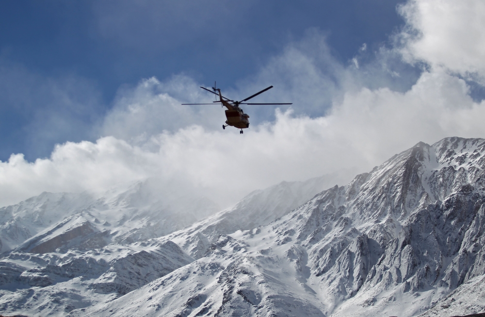A handout picture released on February 19, 2018 by the Tasnim news agency shows members of a rescue team helicopter searching for the wreckage of Aseman Airlines flight EP3704 in Iran's Zagros mountain range. AFP PHOTO / HO / TASNIM NEWS