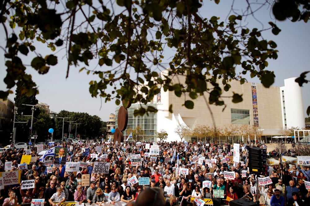 Protesters hold signs calling upon Israeli Prime Minister Benjamin Netanyahu to step down during a rally in Tel Aviv, Israel February 16, 2018. REUTERS/Amir Cohen
