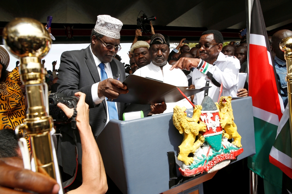 FILE PHOTO Kenyan opposition leader Raila Odinga (C) of the National Super Alliance (NASA) is assisted by lawyer Miguna Miguna (L) and James Orengo as he takes a symbolic presidential oath of office in front of his supporters in Nairobi, Kenya January 30,