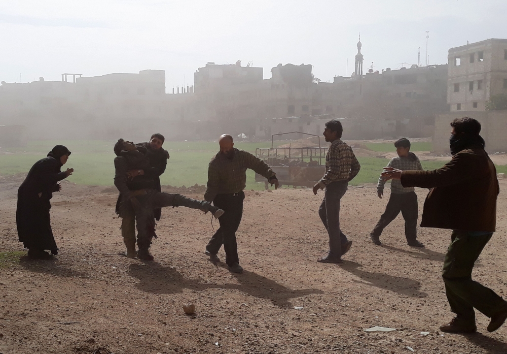 Syrians carry a wounded man who lost in his leg in air strikes on Saqba in Syria's rebel-held Eastern Ghouta area on February 20, 2018. AFP / Msallam ABDALBASET
