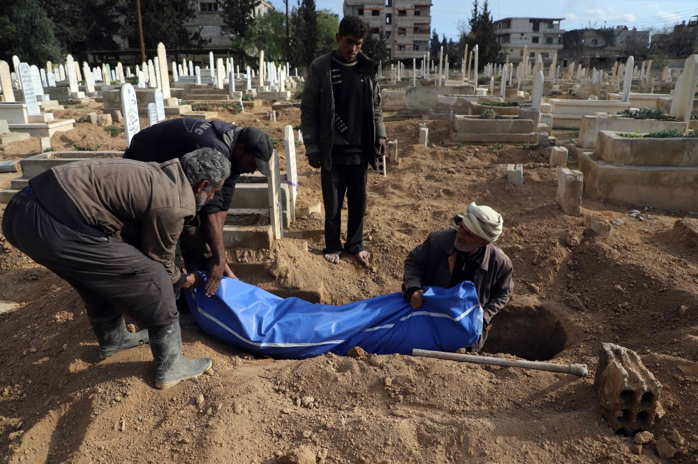 Syrians prepare to bury a body in Kafr Batna, in the besieged Eastern Ghouta region on the outskirts of the capital Damascus on February 22, 2018. AFP / Amer Almohibany
